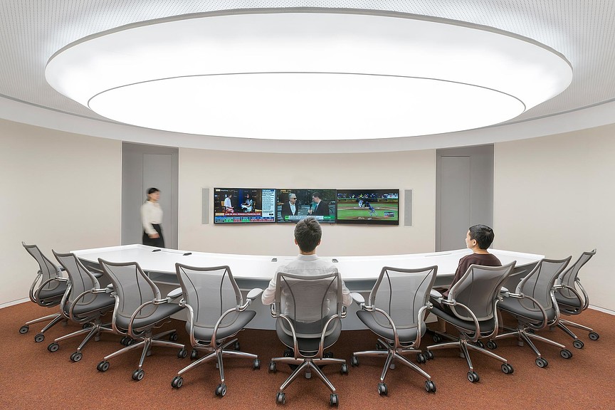 A group of people sitting in chairs in a room with a large screen.